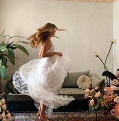 a woman in a white dress is walking through a living room