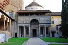 an old building with a dome on the top and green grass in front of it