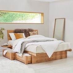 a bed sitting in the middle of a bedroom next to a mirror and planter