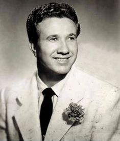 a black and white photo of a man in a suit with a flower on his lapel