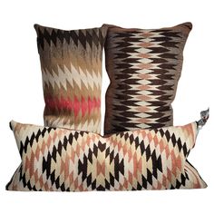 three pillows with different patterns on them, one is brown and the other is pink