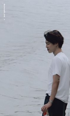 a young man standing next to the water