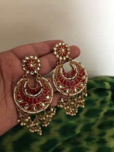 The beautiful earrings are handcrafted by our skilled Indian craftsmen in red enamelled work and Kundan embellishments. The elegant pearl drops tassels at the bottom add a perfect glamour to the stunning pair. Length of earrings: 12 cms Width of earrings: 4.5 cms Pick them up and shine at your next occasion! All our pieces are in stock and will be dispatched with in 24 to 48 hours of order. Orders received during the weekend will be dispatched on Monday Round Hand Set Chandelier Earrings As Gift, Ceremonial Red Meenakari Jhumkas, Red Hand Set Danglers For Gift, Red Hand-set Chandbali Danglers, Red Chandbali Hand Set Danglers, Red Chandbali Danglers With Hand Set, Red Hand Set Chandbali Danglers, Hand Set Red Jhumkas For Festive Occasions, Red Hand Set Jhumkas For Festive Occasions