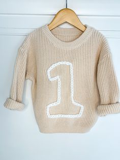 Follow on instagram for more photos of our sweaters! @greenmoonbabyco Use code SIBLINGS10 for a 10% discount on an order of 2 items or more. First birthday sweater, ONE sweater, Keepsake sweater, first birthday outfit, birthday sweater, birthday outfit Each sweater is hand-embroidered with a block number of your choosing, 1-9! This makes an adorable outfit for a birthday party or birthday photos!  Sweater is an oversized fit. If you order child's normal size it will fit oversized, or you can order a size up for additional room for growth. Embroidery comes in regular yarn or chunky yarn. See photos for the color options in each style. Designs can include confetti, flowers, confetti, or message me to add something custom! If you are interested in a sweater color, embroidery color, or design Cute Sweater For Birthday In Winter, Cute Crew Neck Birthday Sweater, Cute Crew Neck Sweater For Birthday, White Tops For Birthday And Winter, White Top For Birthday In Winter, Outfit For A Birthday Party, Embroidered Number, Birthday Sweater, Sweater Embroidery