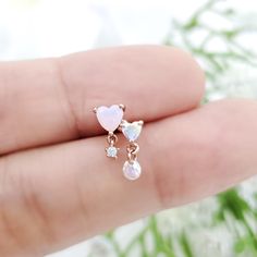 a hand holding a tiny pink heart and two small white hearts on it's finger