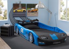 a child's race car bed in a blue room with pictures on the wall