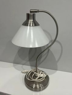 a table lamp with a white shade sitting on top of a counter next to a drawer