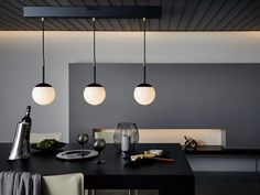 a dining room table with three lights hanging from it's ceiling and two wine glasses on the table