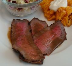 a white plate topped with meat and coleslaw next to a bowl of coleslaw