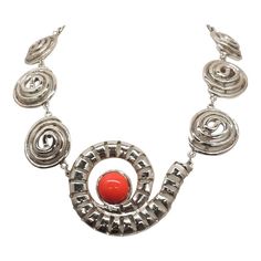 This is part of Chairish’s Costume Jewelry assortment.  1970s Modernist rhodium plated spiral links with cabochon faux-carnelian center and box clasp with a single clear round rhinestone on it necklace. Marked "U.C. Ugo Correani Made in Italy." Center:  2 inches long. Overall measures: 7 1/2 inches long by 5 1/2 inches wide. Interior circumference about 17 1/2 inches. Condition: Very good except that there is crazing to the metal coating on the clasp, which may be a problem at a later date, but Modern Red Metal Jewelry, Retro Silver Metal Jewelry, Modern Red Cabochon Jewelry, Modern Spiral Jewelry For Formal Occasions, Modern Spiral Jewelry For Formal Events, Vintage Metal Necklace With Polished Finish, Modernist Silver Jewelry With Cabochon, Retro Silver Round Necklace, Metal Cabochon Necklace In Costume Jewelry Style