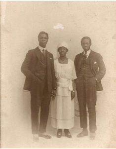 an old black and white photo of three people in formal wear standing next to each other