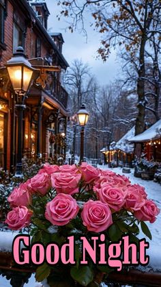 a vase filled with pink roses sitting on top of a table next to a building