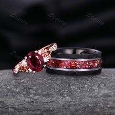 two wedding bands with red and white stones on them, one has a ring in the shape of an arrow