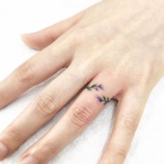 a woman's hand with a small flower tattoo on her left ring finger,