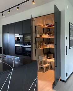 an open kitchen with black cabinets and marble counter tops, along with stainless steel appliances