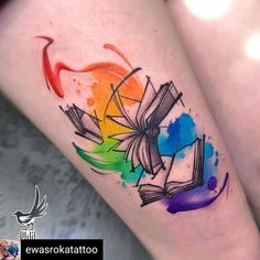 a colorful tattoo on the leg of a woman with an open book and rainbow colors