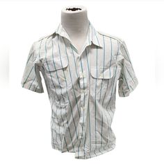 This vintage Oleg Cassini shirt is a stylish addition to any wardrobe. With a blue striped pattern and collared neckline, it's perfect for a retro-themed outfit. The short-sleeved shirt features a button-down closure and pockets for added convenience. Made from breathable woven fabric, it's suitable for all seasons. The size is a regular fit L, and the shirt is designed for men. Whether you're looking for a casual or formal button-up shirt, this Oleg Cassini shirt is a great choice. Blue Collared Shirt With Vertical Stripes, Retro Cotton Shirt With Collared Neckline, Striped Shirt With Collar For Work, White Horizontal Stripe Button-up Top, Classic Pinstripe Collared Top, Classic Collared Pinstripe Tops, Classic Striped Shirt With Camp Collar, Striped Collared Shirt With Placket, Striped Fitted Shirt With Button Closure