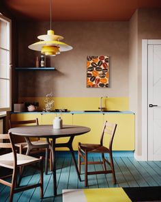 a table and chairs in a room with yellow walls, blue flooring and wooden floors