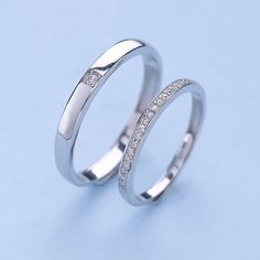 two white gold wedding bands with diamonds on each side, set against a blue background