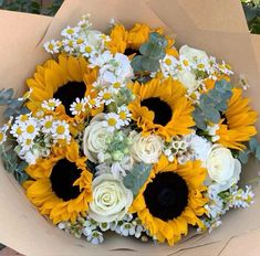 a bouquet of sunflowers and white roses in a box