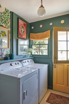 a washer and dryer in a green room next to a door with pictures on the wall