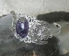 This beautiful silver plated filigree cuff bracelet has a silver plated crescent moon design and an amethyst setting with silver plated embellishments. Adjustable. Silver Gemstone Jewelry In Art Nouveau Style, Elegant Silver Amethyst Cuff Bracelet, Elegant Silver Amethyst Bangle, Art Nouveau Silver Gemstone Jewelry, Antique Silver Gemstone Bracelet, Vintage Silver Amethyst Bracelets, Handmade Silver Amethyst Cuff Bracelet, Ornate Silver Bracelets With Jewels, Ornate Silver Jeweled Bracelets