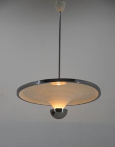 a light fixture hanging from the ceiling in a room with white walls and flooring