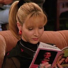 a woman reading a magazine while sitting on a brown couch with her hair in pigtails