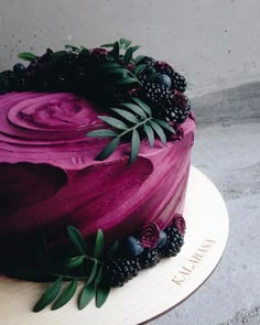 a purple cake with berries and leaves on top