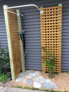 an outdoor shower in front of a house with stone walkways and wooden privacy screens