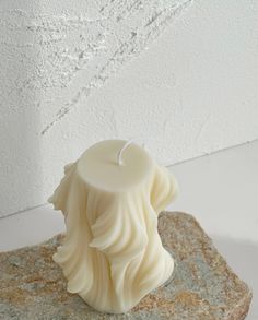 a white candle sitting on top of a stone block