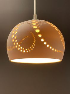 a white light hanging from a ceiling with circles and dots on the bottom of it