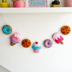 there are donuts hanging on the wall with little miss deliciouss decorations above them