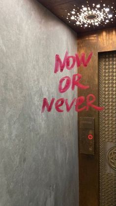 graffiti on the side of a wall next to a door with words now or never written on it