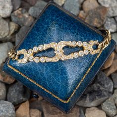 a blue leather wallet sitting on top of rocks next to some gravel and stones with a gold chain around it