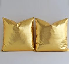 two gold pillows sitting on top of each other