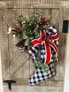 a christmas stocking hanging on the side of a wooden door with holly and berries