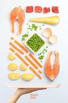 a person holding a tray with different types of food on it that includes fish, peas, broccoli and carrots