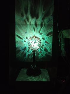 a lamp is lit up in the dark with green and white designs on it's surface