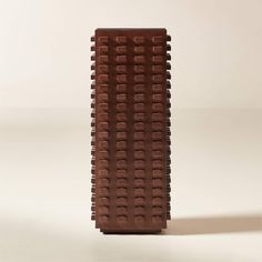 a tall brown vase sitting on top of a white table covered in lots of chocolate squares