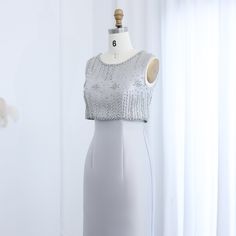 a white dress on a mannequin in front of a window with curtains behind it