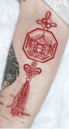 a woman's arm with a red tattoo on it and an image of a house