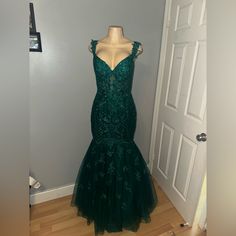 a green dress is on display in front of a white door with a wooden floor