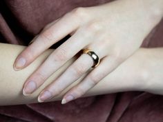 a woman's hand with a gold ring on her left wrist, resting against a velvet blanket