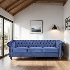 a blue couch sitting on top of a hard wood floor next to a glass door