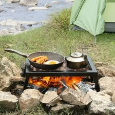 a campfire with pots and pans cooking over it