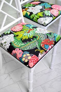 two white chairs with colorful floral cushions on them