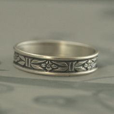 Mens Wedding Ring Silver Romance with an Edge Band Silver Mens Ring Silver Wedding Band Mens Promise Ring Womens Wedding Band for Her This is the wider version of our very popular Romance design, which can be found here: https://www.etsy.com/listing/96317363 Both can be purchased together as a set here: https://www.etsy.com/listing/615866348 The wider option is created from the same pre-patterned silver stock. We then expertly join an 18 gauge/1mm full round silver stock to either side for a fin Decorative Band Rings For Marriage, Engraved Wedding Band Rings, Silver Wedding Rings With Decorative Band, Classic Marriage Rings With Band Shape, Classic Adjustable Engraved Ring For Wedding, Decorative Promise Ring Band, Classic Engraved Toe Ring For Wedding, Adjustable Band Wedding Rings, Heirloom Wedding Band Adjustable