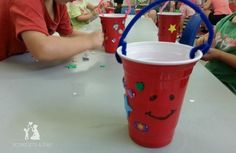 two children sitting at a table with cups in front of them and one child smiling