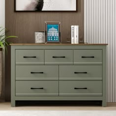 a green dresser in a living room with pictures on the wall and plants next to it